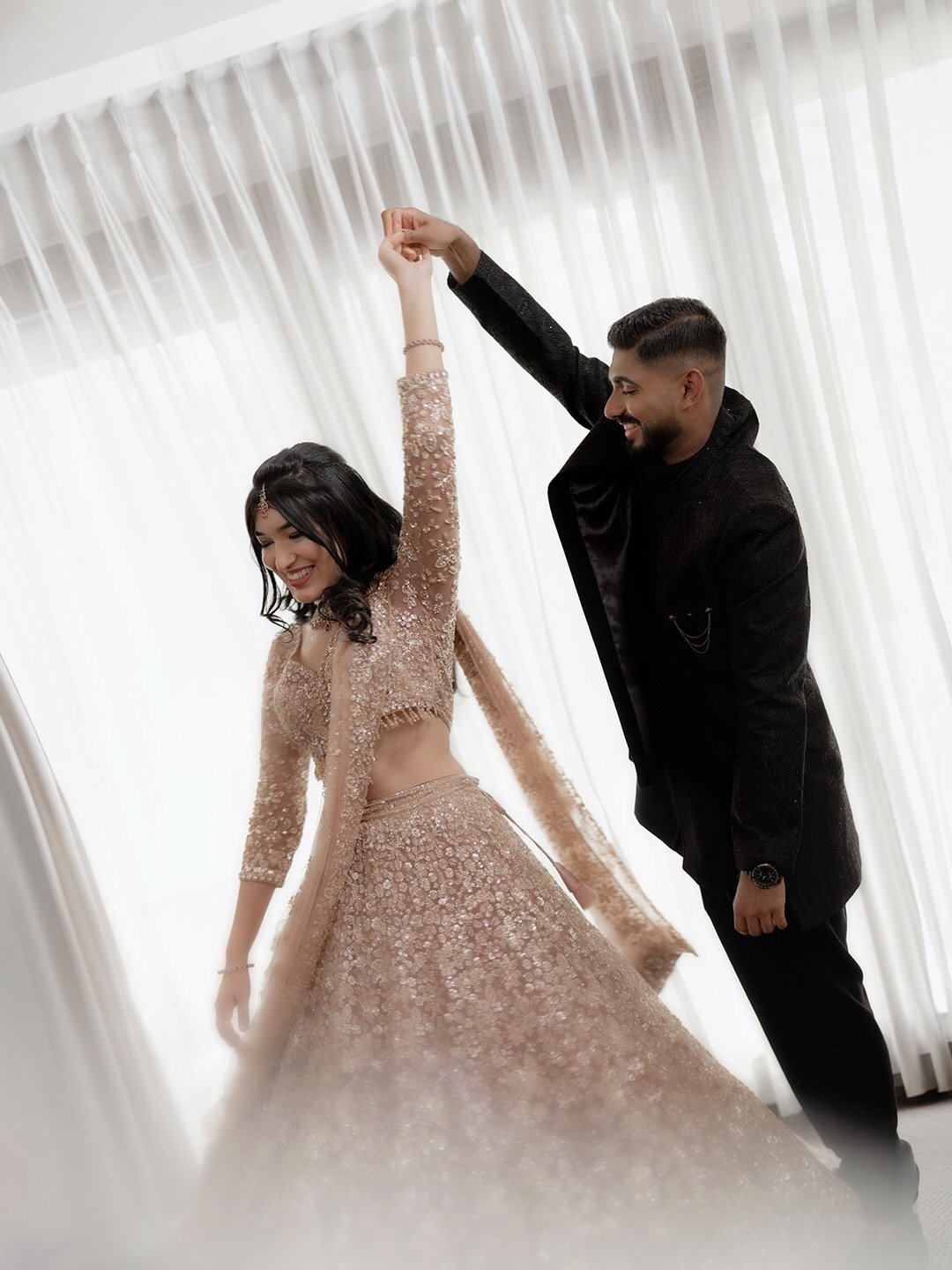 An engaged couple dancing together in soft window light